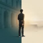 Un homme debout à la frontière entre un environnement urbain sombre et un espace de travail lumineux et épuré.