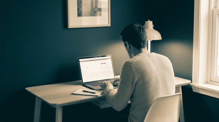 Homme travaillant sur son ordinateur portable à son bureau dans un environnement calme.