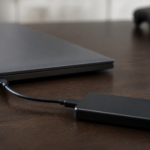 Disque SSD externe relié à un ordinateur portable avec une manette de jeu en arrière-plan